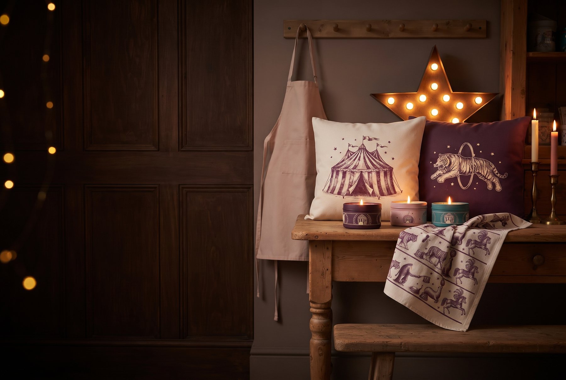 Circus-print cushion covers, candles in printed tins, tea towels and an apron arranged in a shop window